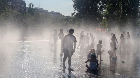 Varios niños se refrescan en una fuente durante la tercera ola de calor en Madrid, en el parque Madrid Río.