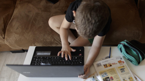 Un alumno de primaria hace los deberes de la asignatura de Inglés con varios libros y un ordenador a menos de un mes de terminar en casa el curso escolar 2019-2020 por la pandemia del Covid-19, en Madrid (España) a 20 de mayo de 2020.