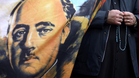Un sacerdote sostiene un rosario junto a una bandera con el retrato del dictador Francisco Franco, en las afueras del cementerio Mingorrubio-El Pardo, el 24 de octubre. REUTERS / Sergio Perez Un sacerdote sostiene un rosario junto a una bandera con el retrato del dictador Francisco Franco, en las afueras del cementerio Mingorrubio-El Pardo, el 24 de octubre. REUTERS / Sergio Perez