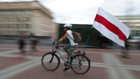 Una mujer en bicicleta lleva la histórica bandera presoviética de Bielorrusia, durante las manifestaciones contra los resultados de las elecciones presidenciales, que dieron la victoria a Aleksandr Lukashenko, en Minsk. REUTERS/Vasily Fedosenko Una mujer en bicicleta lleva la histórica bandera presoviética de Bielorrusia, durante las manifestaciones contra los resultados de las elecciones presidenciales, que dieron la victoria a Aleksandr Lukashenko, en Minsk. REUTERS/Vasily Fedosenko