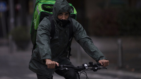 Un rider (repartidor) trabaja bajo la lluvia protegido con un impermeable, en Sevilla . E.P./María José López Un rider (repartidor) trabaja bajo la lluvia protegido con un impermeable, en Sevilla . E.P./María José López