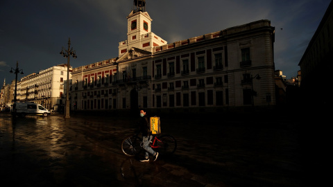 Un repartidor de Glovo con mascarilla pasa por una prácticamente desierta Puerta del Sol, de Madrid. REUTERS/Juan Medina Un repartidor de Glovo con mascarilla pasa por una prácticamente desierta Puerta del Sol, de Madrid. REUTERS/Juan Medina
