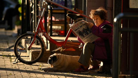 Una mujer lee el periódico en una calle de Pekín. AFP/Noel Celis Una mujer lee el periódico en una calle de Pekín. AFP/Noel Celis