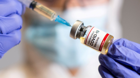 FILE PHOTO: A woman holds a small bottle labeled with a "Coronavirus COVID-19 Vaccine" sticker and a medical syringe in this illustration taken October 30, 2020. REUTERS/Dado Ruvic/File Photo FILE PHOTO: A woman holds a medical syringe and a small bottle labeled "Coronavirus COVID-19 Vaccine