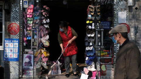 Una mujer con mascarilla limpia la entrada de su tienda en Pekín.. REUTERS/Carlos Garcia Rawlins Una mujer con mascarilla limpia la entrada de su tienda en Pekín.. REUTERS/Carlos Garcia Rawlins