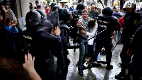 Un hombre intenta proteger a una mujer de los porrazos de la Policía Nacional, el 1 de octubre de 2017. - Jordi Play / ACN Un hombre intenta proteger a una mujer de los porrazos de la Policía Nacional, el 1 de octubre de 2017. - Jordi Play / ACN