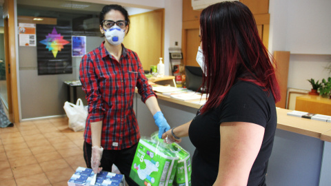 Una treballadora de l'Associació Benestar i Desenvolupament (ABD) entrega bolquers i llet a una usuària. Foto cedida per ABD Una treballadora de l'Associació Benestar i Desenvolupament (ABD) entrega bolquers i llet a una usuària. Foto cedida per ABD