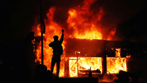 Un manifestante delante de una edificio ardiendo durante los disturbios desatados en Minesota tras la muerte de George Floyd, un ciudadano negro, a manos de la policía.- REUTERS Un manifestante delante de una edificio ardiendo durante los disturbios desatados en Minesota tras la muerte de George Floyd, un ciudadano negro, a manos de la policía.- REUTERS