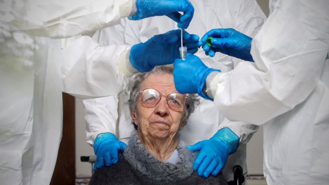 Un mujer observa al personal sanitario tras hacerse una prueba de coronavirus en la Fundación Comendador Joaquim De Sa Couto Foundation en Santa Maria da Feira, Portugal. EFE/ Jose Coelho