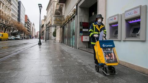 Una trabajadora del servicio de Correos realiza su trabajo por las calles casi desiertas de Zaragoza el pasado lunes. EFE/Javier Cebollada Una trabajadora del servicio de Correos realiza su trabajo por las calles casi desiertas de Zaragoza el pasado lunes. EFE/Javier Cebollada