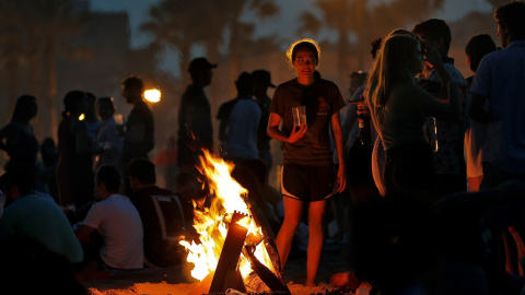 Una joven observa las llamas de la hoguera que ha encendido junto a un grupo de amigos para celebrar la Noche de San Juan | EFE Una joven observa las llamas de la hoguera que ha encendido junto a un grupo de amigos para celebrar la Noche de San Juan | EFE