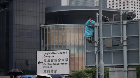 Un manifestante permanece encaramado sobre una señal de tráfico durante las protestas en contra de la polémica ley de extradición ante el Consejo Legislativo en Hong Kong, China. EFE / Jerome Favre