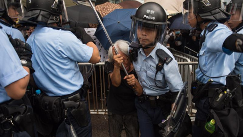 Un policía aleja a una manifestante durante un mitin contra las enmiendas a un proyecto de ley de extradición cerca del Consejo Legislativo en Hong Kong, China, el 12 de junio de 2019. EFE / Jerome Favre