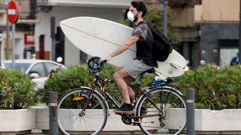Un surfista protegido con mascariilla carga su tabla en bici hacia la playa de la Malvarrosa, en Valencia, hoy quincuagésimo sexto día del estado de alarma. EFE/ Juan Carlos Cárdenas Un surfista protegido con mascariilla carga su tabla en bici hacia la playa de la Malvarrosa, en Valencia, hoy quincuagésimo sexto día del estado de alarma. EFE/ Juan Carlos Cárdenas