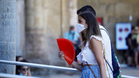 Una mujer protegida con unas mascarilla mientras se abanica para aliviar las altas temperaturas de este jueves en Córdoba. | EFE Una mujer protegida con unas mascarilla mientras se abanica para aliviar las altas temperaturas de este jueves en Córdoba. | EFE