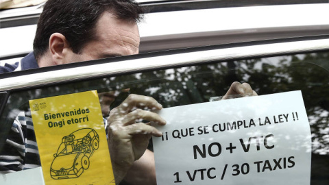 Un taxista pega en su taxi un cartel de protesta contra el incumplimiento de la proporción 1/30 entre licencias VTC y taxi. EFE Un taxista pega en su taxi un cartel de protesta contra el incumplimiento de la proporción 1/30 entre licencias VTC y taxi. EFE