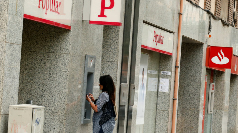 Una mujer saca dinero en un cajero de una entidad del Banco Popular que si sitúa junto a otra del banco Santander.REUTERS/Albert Gea Una mujer saca dinero en un cajero de una entidad del Banco Popular que si sitúa junto a otra del banco Santander.REUTERS/Albert Gea