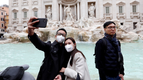Turistas fotografiándose en la Fontana de Trevi con mascarillas protectoras para evitar el contagio por coronavirus. REUTERS