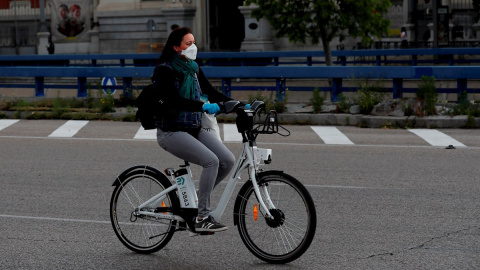 Una mujer con mascarilla y guantes usa una bicicleta del servicio BiciMAD, en Madrid. EFE/Chema Moya Una mujer con mascarilla y guantes usa una bicicleta del servicio BiciMAD, en Madrid. EFE/Chema Moya