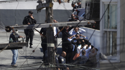 Las transeúntes están siendo evacuados con las manos por encima de sus cabezas por orden de la policía en el área de un incidente de tiroteo en una instalación de United Parcel Service (UPS) en San Francisco, California, EE.UU. 14 de junio de 2017. Las transeúntes están siendo evacuados con las manos por encima de sus cabezas por orden de la policía en el área de un incidente de tiroteo en una instalación de United Parcel Service (UPS) en San Francisco, California, EE.UU. 14 de junio de 2017.