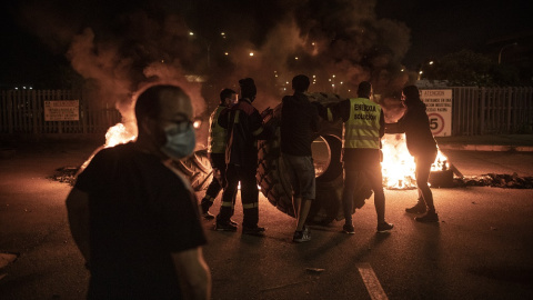 Trabajadores de Alcoa alimentan el fuego de la barricada con una rueda de camión a la entrada de la factoría. MANU BRABO Trabajadores de Alcoa alimentan el fuego de la barricada con una rueda de camión a la entrada de la factoría. MANU BRABO