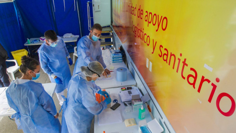 Unos enfermeros procesan tubos con pruebas PCR durante la realización de test voluntarios a jóvenes en Laviana, Asturias. / EFE