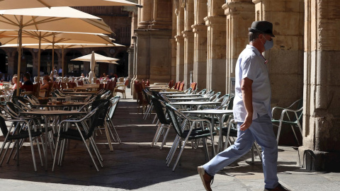 Un hombre con mascarilla pasa frente a una terraza de un restaurante de la plaza mayor de Salamanca, este miércoles. | EFE Un hombre con mascarilla pasa frente a una terraza de un restaurante de la plaza mayor de Salamanca, este miércoles. | EFE