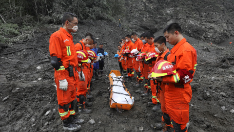 Trabajadores de rescate chinos rinden un minuto de silencio ante el cuerpo de una de las victimas del alud que sepultó una aldea del Tibet./REUTERS Trabajadores de rescate chinos rinden un minuto de silencio ante el cuerpo de una de las victimas del alud que sepultó una aldea del Tibet./REUTERS