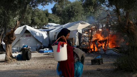 Una mujer trata de recuperar alguna de sus pertenencias, mientras el fuego sigue consumiendo las carpas del campamento de refugiados de Moria. - EFE Una mujer trata de recuperar alguna de sus pertenencias, mientras el fuego sigue consumiendo las carpas del campamento de refugiados de Moria. - EFE