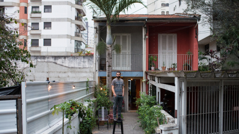 Gustavo posando en frente de la casa que empezó a rentar en el verano de 2015 en Vila Madalena. Las casas cercanas fueron demolidas hace 1 mes y las torres serán construidas en 6 meses. Convenció al propietario de alquilarle la casa en lugar de venderl Gustavo posando en frente de la casa que empezó a rentar en el verano de 2015 en Vila Madalena. Las casas cercanas fueron demolidas hace 1 mes y las torres serán construidas en 6 meses. Convenció al propietario de alquilarle la casa en lugar de venderl