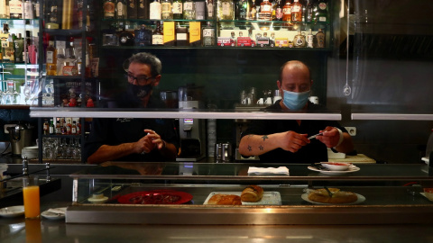 Dos camareros con mascarilla, tras la barra de un bar del madrileño barrio de Vallecas. REUTERS/Sergio Perez Dos camareros con mascarilla, tras la barra de un bar del madrileño barrio de Vallecas. REUTERS/Sergio Perez