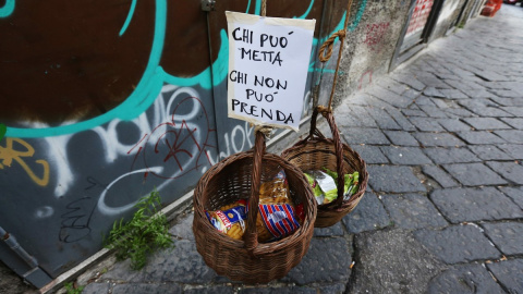 “Si puedes, pon; si no puedes, toma”, reza la carta introducida en esta cesta solidaria en Napoles.- AFP / Carlo Hermann