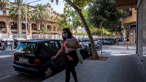 Una mujer con mascarilla camina por la avenida del Arquitecte Bennàssar en Palma, donde el Govern ha anunciado nuevas medidas para contener los contagios | EFE Una mujer con mascarilla camina por la avenida del Arquitecte Bennàssar en Palma, donde el Govern ha anunciado nuevas medidas para contener los contagios | EFE