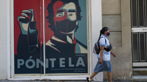 Una mujer pasa junto a una pancarta en la que se ve a Fernando Simón fomentando el uso de la mascarilla.- AFP Una mujer pasa junto a una pancarta en la que se ve a Fernando Simón fomentando el uso de la mascarilla.- AFP