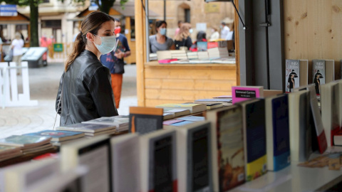 Una mujer con mascarilla en la feria del libro de Oviedo este sábado. / EFE