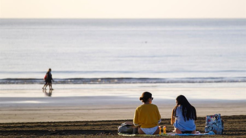 Dos jóvenes charlan en la playa de Maspalomas, en el sur de Gran Canaria, este martes a primera hora de la mañana, en un día con el cielo totalmente despejado. Dos jóvenes charlan en la playa de Maspalomas, en el sur de Gran Canaria, este martes a primera hora de la mañana, en un día con el cielo totalmente despejado.
