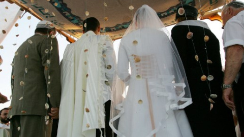 Pareja israelí bajo un altar judío durante su ceremonia de boda en el asentamiento de Neve Dekalim en la Franja de Gaza meridional. AFP PHOTO / DAVID FURST Pareja israelí bajo un altar judío durante su ceremonia de boda en el asentamiento de Neve Dekalim en la Franja de Gaza meridional. AFP PHOTO / DAVID FURST