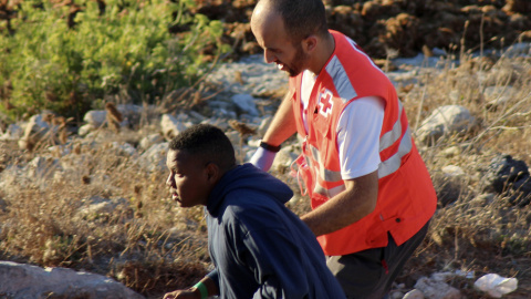 Un efectivo de la Cruz Roja con uno de los inmigrantes que ha sido abandonado, junto con otros once de los cuales uno ha fallecido, por seis motos de agua que los transportaban a pocos metros de la orilla de una de las playas de la barriada de Benzú, en Un efectivo de la Cruz Roja con uno de los inmigrantes que ha sido abandonado, junto con otros once de los cuales uno ha fallecido, por seis motos de agua que los transportaban a pocos metros de la orilla de una de las playas de la barriada de Benzú, en