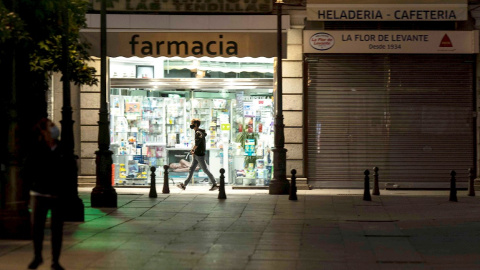 Un hombre pasa junto a una farmacia abierta Un hombre pasa junto a una farmacia abierta