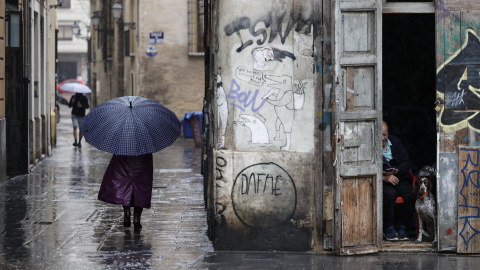 Una persona camina bajo la lluvia por las calles del centro histórico de València. Una persona camina bajo la lluvia por las calles del centro histórico de València.