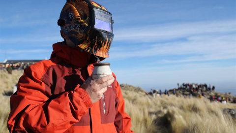 Un hombre observa el eclipse solar total con una máscara de soldar mientras toma mate, este martes, en la ciudad de Merlo, San Luis (Argentina). EFE