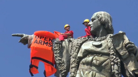 Dos activistes de Proactiva Open Arms col·loquen una armilla gegant a l'estàtua de Colon. CCMA