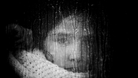 Una niña mira a través del cristal de un autobús camino al campamento de Moria.