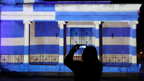 Un hombre toma fotografías frente al antiguo ayuntamiento de Nicosia, iluminado con la bandera griega que marca el 200 aniversario de la Guerra de Independencia de Grecia, en Nicosia, Chipre, el 25 de marzo de 2021. Un hombre toma fotografías frente al antiguo ayuntamiento de Nicosia, iluminado con la bandera griega que marca el 200 aniversario de la Guerra de Independencia de Grecia, en Nicosia, Chipre, el 25 de marzo de 2021.