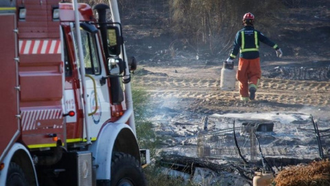 Un bombero trabaja en los restos de un incendio en un asentamiento chabolista de Lepe, en una imagen de archivo. Un bombero trabaja en los restos de un incendio en un asentamiento chabolista de Lepe, en una imagen de archivo.