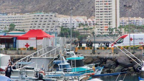 Llegada de cayuco a Puerto de Los Cristianos, Tenerife con turistas al lado que van a bucear Llegada de cayuco a Puerto de Los Cristianos, Tenerife con turistas al lado que van a bucear