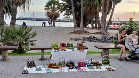 M.N. vende bolsos artesanos hechos con cartones de leche en la playa de Los Cristianos, frente al puerto donde llegó en cayuco. M.N. vende bolsos artesanos hechos con cartones de leche en la playa de Los Cristianos, frente al puerto donde llegó en cayuco.