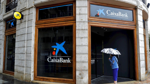 Una mujer observa el interior de la oficina de Caixabank en la plaza del Ayuntamiento de Valencia. EFE/Manuel Bruque Una mujer observa el interior de la oficina de Caixabank en la plaza del Ayuntamiento de Valencia. EFE/Manuel Bruque