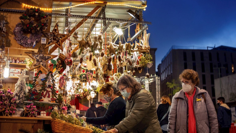 Varias personas junto a un mercadillo navideño este lunes en el centro de Barcelona. EFE/Enric Fontcuberta