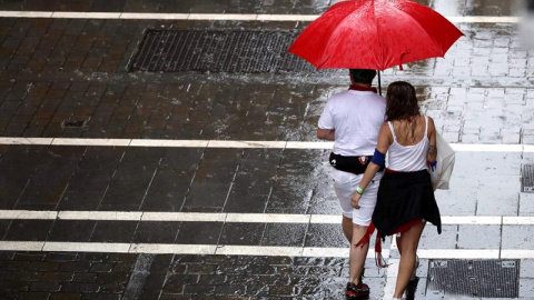 Dos personas se protegen de la lluvia en una de las céntricas calles de Pamplona durante la fiesta de San Fermín. Navarra está en alerta amarilla este lunes por lluvias y tormentas, según Aemet. EFE/ Javier Lizón Dos personas se protegen de la lluvia en una de las céntricas calles de Pamplona durante la fiesta de San Fermín. Navarra está en alerta amarilla este lunes por lluvias y tormentas, según Aemet. EFE/ Javier Lizón